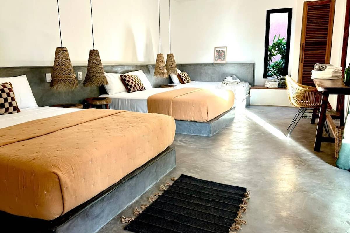 A hotel room with two beds, a dining area, and a large window.