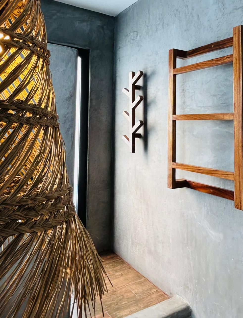 A modern interior with a woven light fixture, a minimalist wall art piece, and a wooden frame structure.