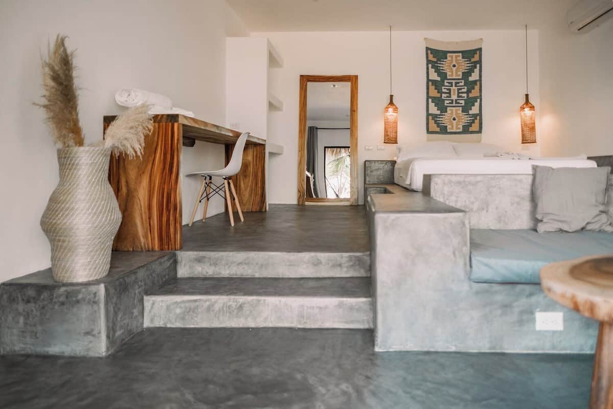 A modern interior with a sofa, a chair, a desk, and a staircase.