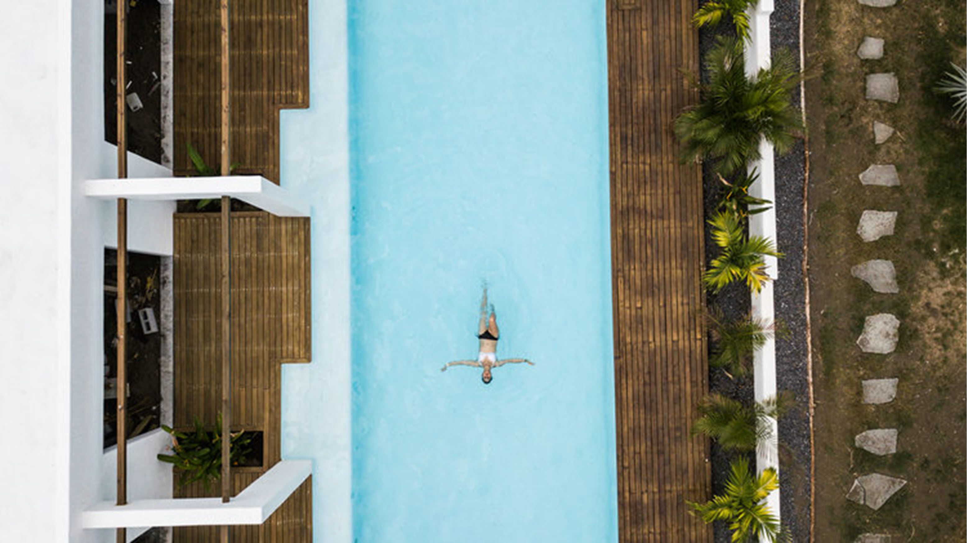 An aerial view of a swimming pool with a person floating in the center.