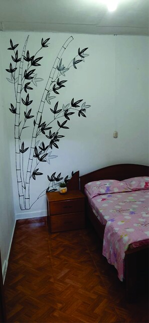 Un dormitorio con cama, mesita de noche, cómoda y un mural de bambú en la pared.