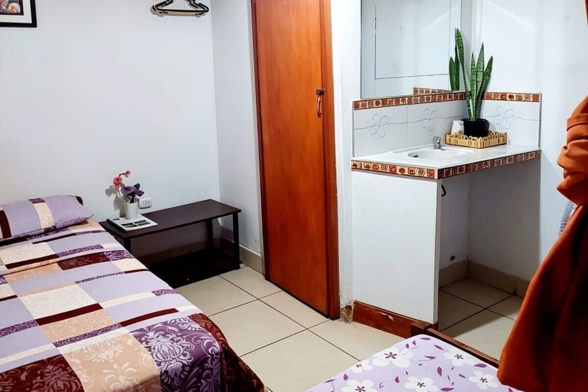 A small, clean room with a bed, a bedside table, a mirror, and a wardrobe.