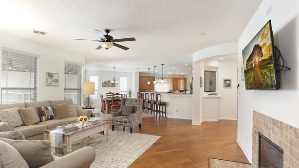 A spacious living room with a sofa, coffee table, and armchairs, a dining area with chairs and a table, a kitchen with wooden cabinets, and a fireplace. - Family friendly 1-story home minutes from Downtown San Antonio (San Antonio)