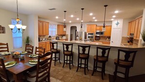 A modern kitchen with wooden cabinets, a central island, and bar stools. - Family friendly 1-story home minutes from Downtown San Antonio (San Antonio)