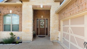 A two-story house with a stone facade, a garage door, and a front door with a wreath. - Family friendly 1-story home minutes from Downtown San Antonio (San Antonio)