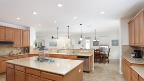 A spacious kitchen with wooden cabinets, a large island, and a dining area with a table and chairs. - Family friendly 1-story home minutes from Downtown San Antonio (San Antonio)
