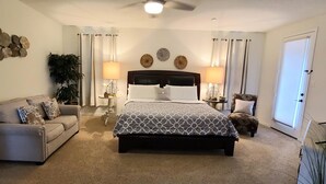 A bedroom with a bed, a sofa, two side tables, decorative wall art, and a plant. - Family friendly 1-story home minutes from Downtown San Antonio (San Antonio)