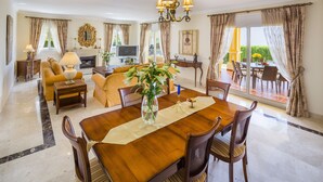 Un vaste espace de vie comprenant un coin repas avec une table, des canapés et une cheminée. Un balcon est également à disposition, avec une table et des chaises.