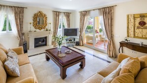 Un salon spacieux doté d’une cheminée, d’un téléviseur et d’un balcon aménagé avec du mobilier d’extérieur.