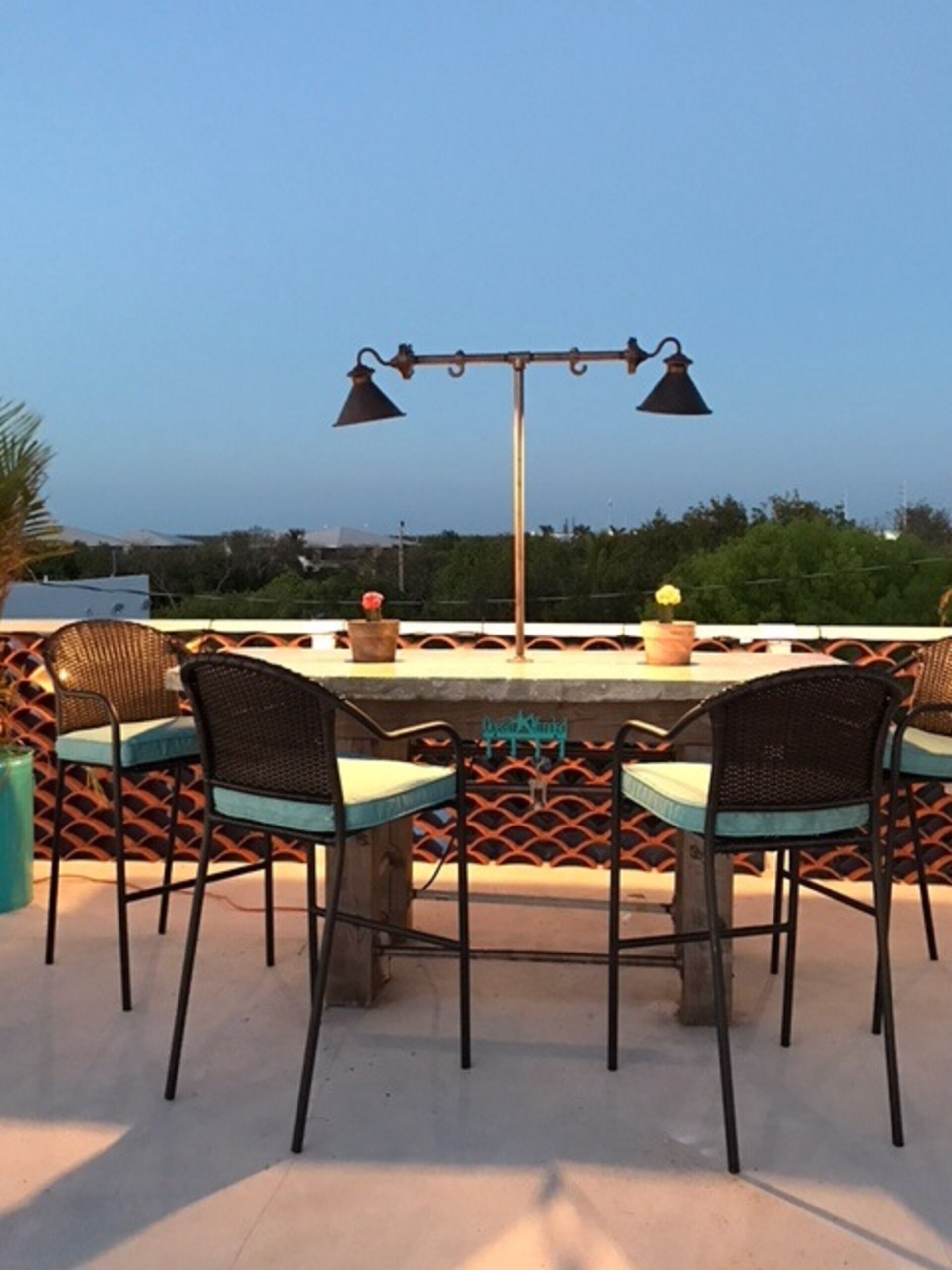 An outdoor patio with a table and chairs, a decorative lamp, and a view of the landscape.