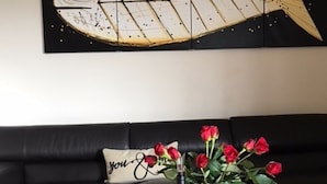 Ein Holztisch mit einer Weinflasche und einem Glas, eine Vase mit roten Rosen und ein Wandbild von einem Fisch.