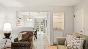 A living room with a patterned sofa, a green sofa, and a lamp. There is a dining area with a table and chairs in the background. - Circle Town hm near the golf course (Austin)