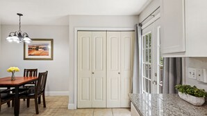 A dining area with a wooden table and chairs, a chandelier, a framed landscape painting, and a white double door. - Circle Town hm near the golf course (Austin)