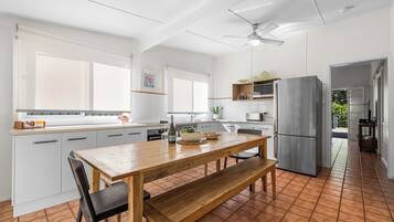 A modern kitchen with white cabinetry, a wooden dining table, and a built-in oven.