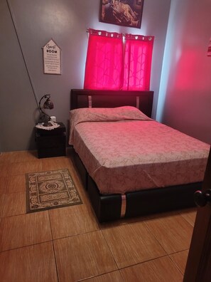 A bedroom with a bed, a nightstand, a lamp, a rug, and a sign on the wall. - Beautiful 3 bedroom modern home (Georgetown)