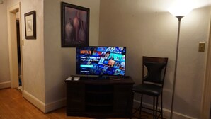 Olohuoneessa on televisio, jossa näkyy Netflixin käyttöliittymä, seinällä on kehystetty taulu ja huoneessa on baarituoli.