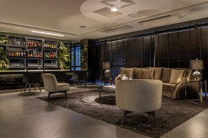 Un área de bar moderna con estanterías llenas de botellas de licor, un sofá y dos sillones.