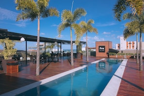 Una piscina al aire libre, sillones reclinables de piscina