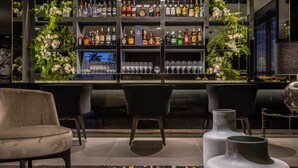 A modern bar area with shelves of liquor bottles, a bar counter, and seating. - LS Hotel (João Pessoa)