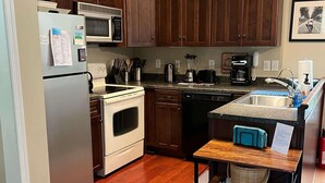A kitchen with wooden cabinets, stainless steel appliances, and a small island with a sink. - Lost River WV-Relaxing 3br/2bath farmhouse-dog friendly-  treetop deck-workspace (Mathias)