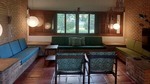 A cozy interior with a green sofa, wooden chairs, and a brick wall. - Pleasant beachfront house on Guaecá beach, São Sebastião, SP (São Sebastião)