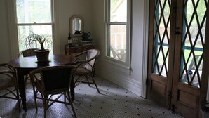 Habitación con una mesa de comedor y sillas, una planta en maceta, un aparador y una ventana que ofrece vista a una terraza de madera.