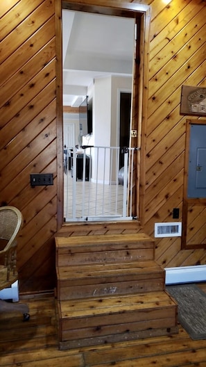 Eine Holztreppe führt zu einem Raum mit einer Spiegelwand, einem Ventilator und einer verschließbaren Tür.