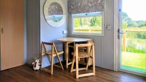 A room with a wooden table and chairs, a decorative plate on the wall, and a window with a view of greenery. - Lillibelles lake house (Ashford)