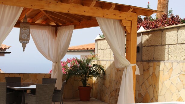 A covered outdoor seating area with a hot tub, wicker chairs, and a potted plant. - Casa Alma 
Beautiful Villa with Mountain & Sea Views
3 Bedrooms 2 Bathrooms (Chayofa)