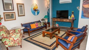 Una sala de estar con sofá, sillones, una mesa de centro y un mueble para televisión.