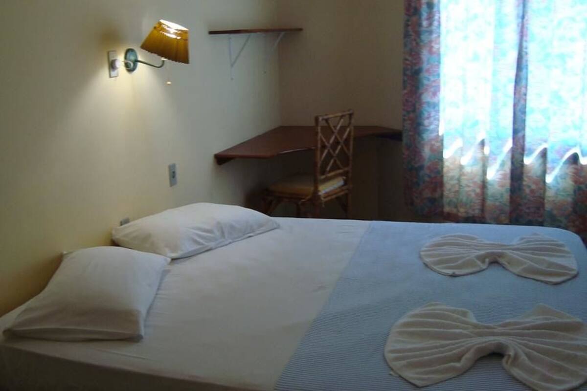 A hotel room with a bed, a desk, and a chair.