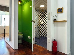A bathroom with a green wall, a checkered shower wall, a toilet, and a fire extinguisher. - N3 Seoul (Seoul)