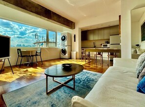 A modern apartment with a large window, a dining area, a kitchen, and a living room with a sofa and a coffee table. - N3 Seoul (Seoul)