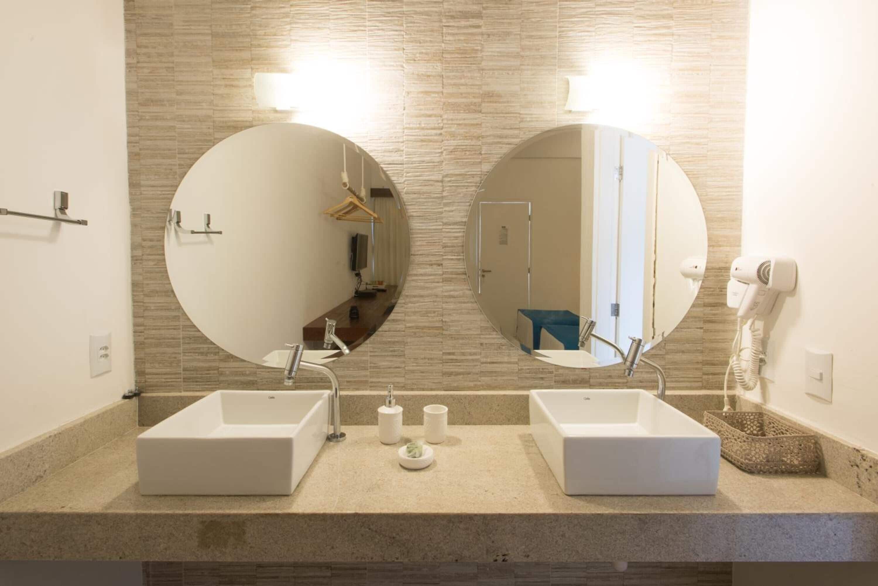 A modern bathroom with two sinks, a large mirror, and a towel rack.