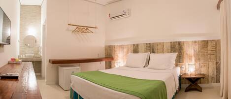 A bedroom with a bed, bedside table, and a small desk with a chair.