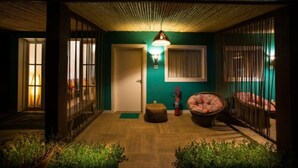 A cozy indoor space with a wooden ceiling, a green wall, and a small seating area with a round table and chairs. - Pousada da Villa (Fernando de Noronha)