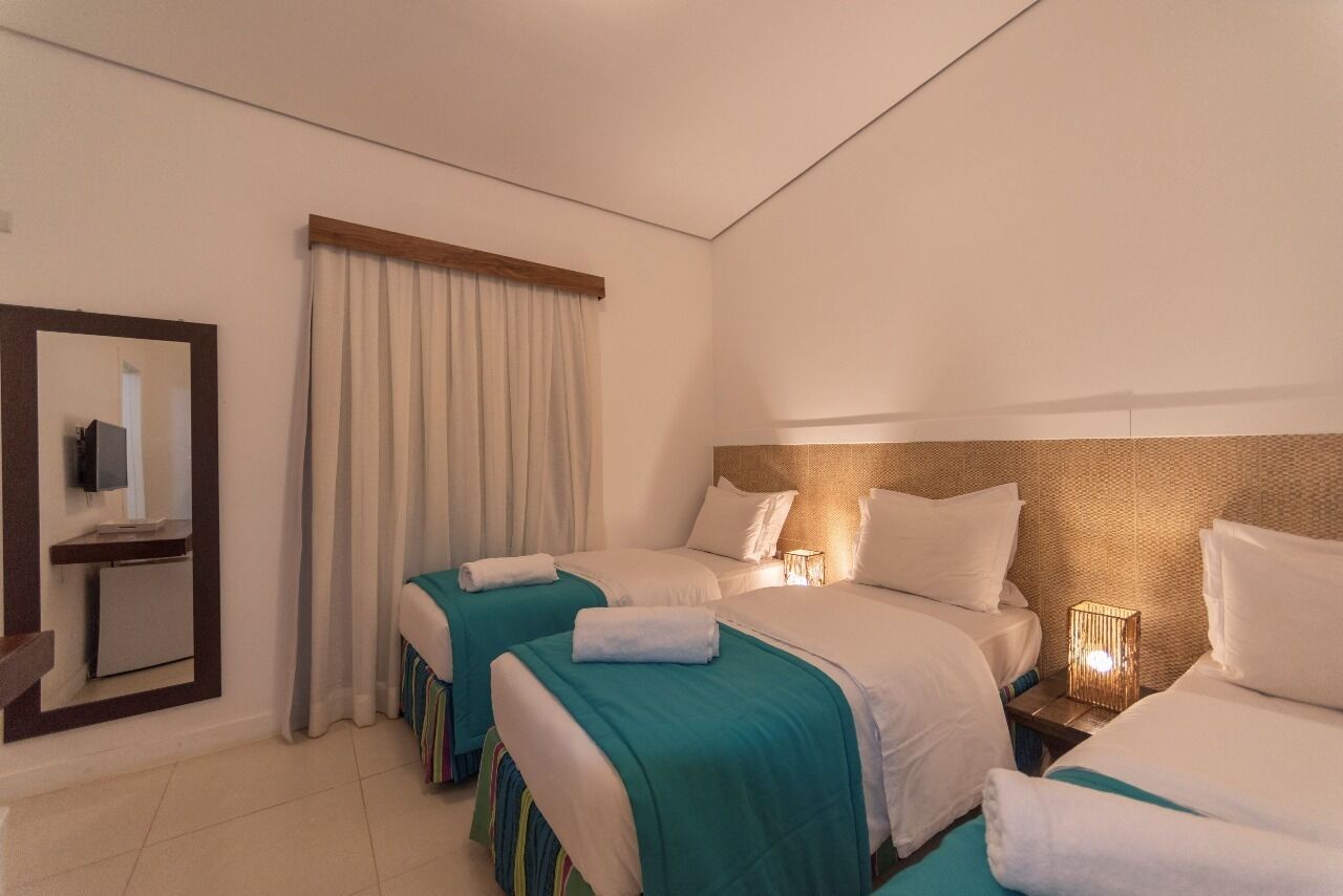A hotel room with two beds, a TV, and a bedside lamp.