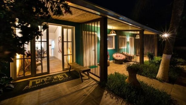 A well-lit outdoor area with a wooden deck, a seating area, and a large window overlooking the interior. - Pousada da Villa (Fernando de Noronha)