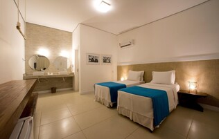 Habitación de hotel con dos camas, un escritorio de madera, un espejo y una mesita de noche con lámpara.
