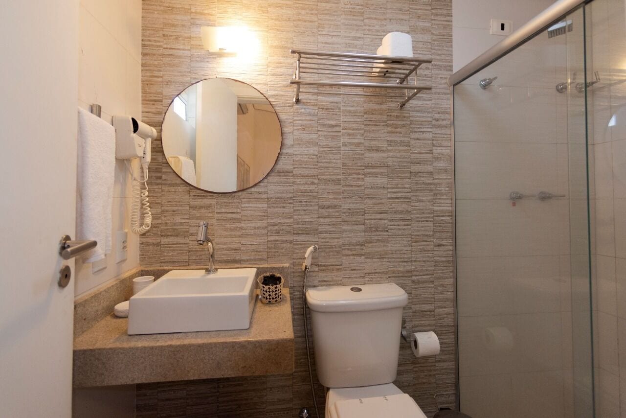 A modern bathroom with a sink, mirror, toilet, and glass shower enclosure.