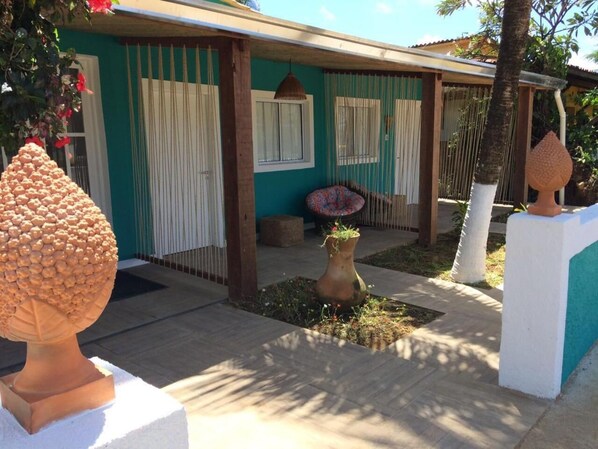 A house with a covered porch, a small garden with a decorative vase, and a large sculptural tree.