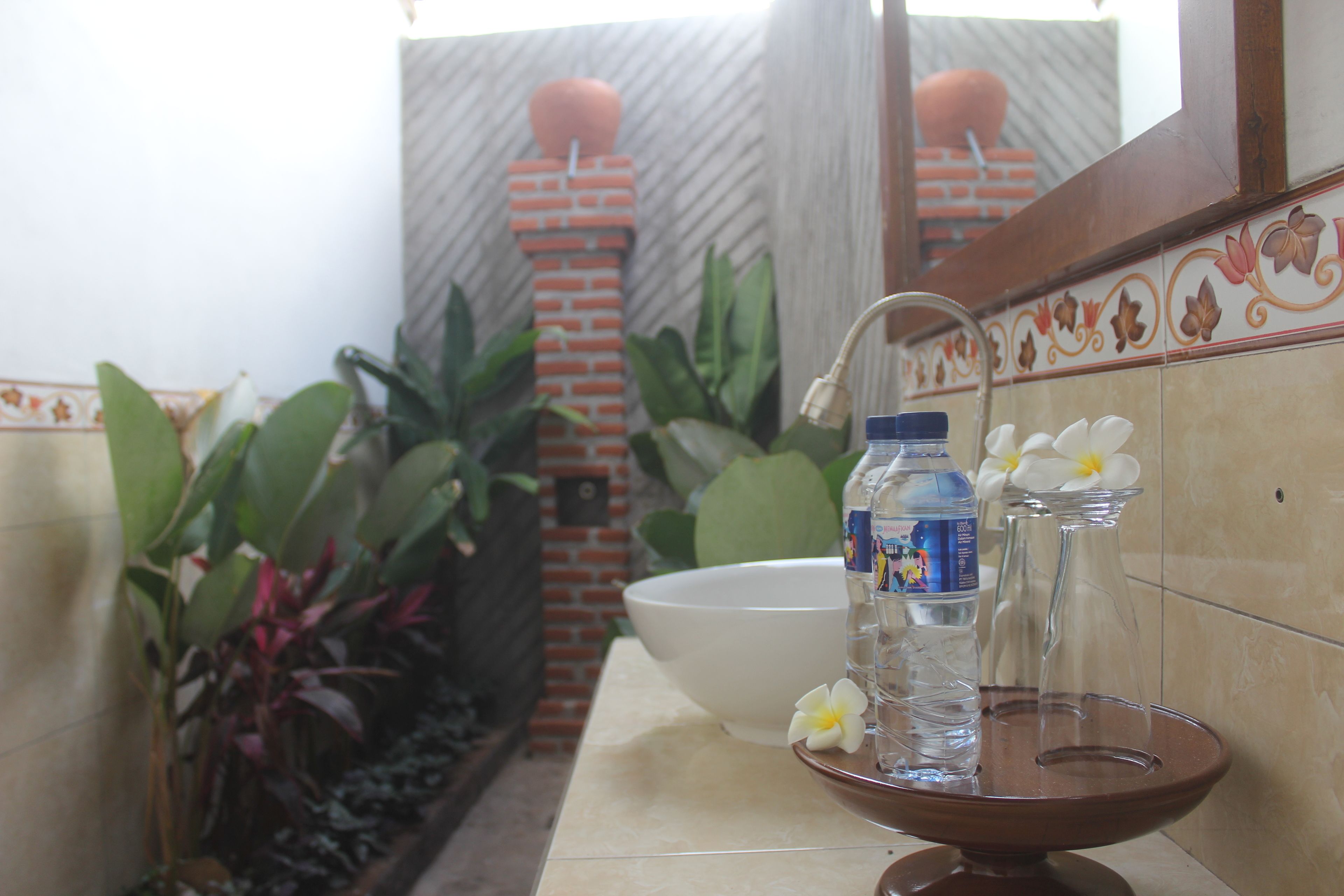 A bathroom with a sink, a mirror, and a decorative brick wall.