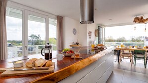 Une cuisine moderne avec un plan de travail en bois, une machine à café et une table pour le petit-déjeuner.