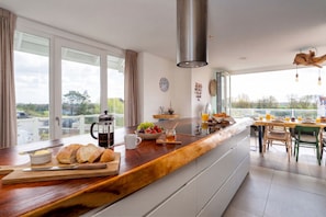 A modern kitchen with a wooden countertop, a coffee maker, and a breakfast setting. - Beautiful family beach house on the dunes with swimming pool (Cadzand)