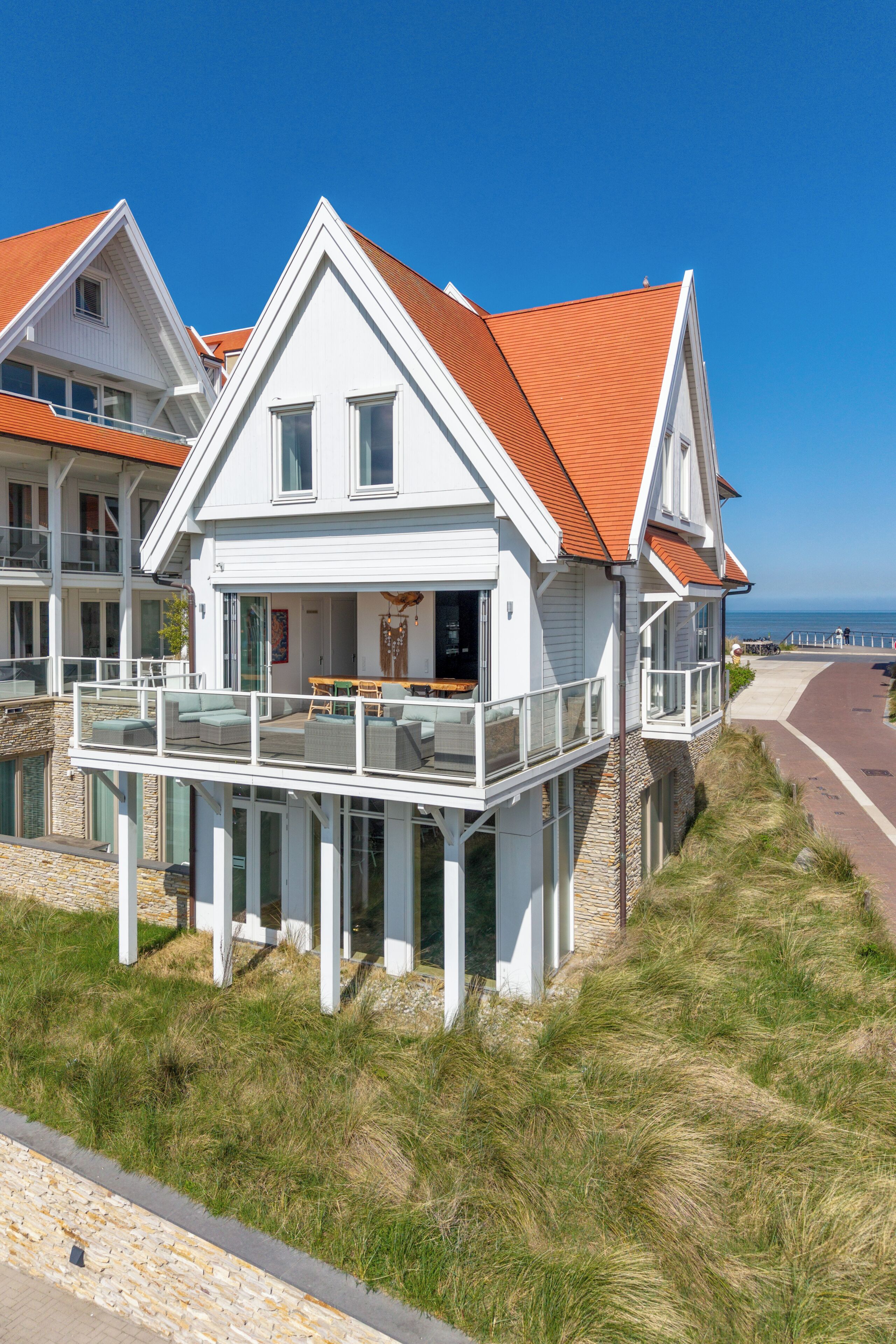 Ein Küstenhaus mit Balkon und Meerblick, auf einem Steinfundament.