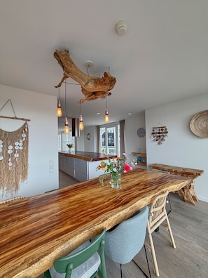 A modern kitchen with a wooden island, pendant lights, and a rustic ceiling.