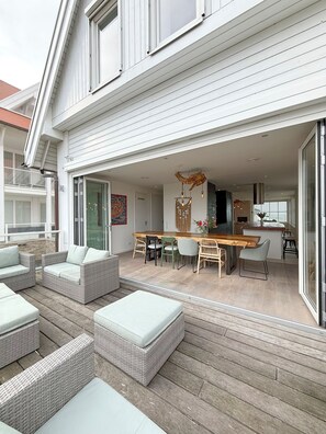 Et moderne hus med en overdækket terrasse, fletningsmøbler og et spiseområde.