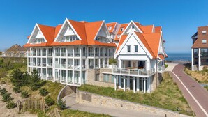 Un bâtiment situé sur la côte, doté de plusieurs étages, de grandes fenêtres et d’un balcon bien visible.