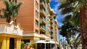 A hotel with a yellow facade, multiple balconies, and outdoor seating areas. - Luxury apartment Bajondillo on the beach (TORREMOLINOS)