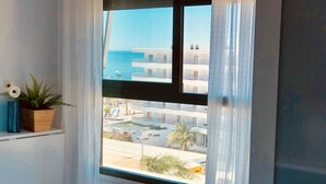 A window with a view of a coastal area, a potted plant, and a curtain. - Luxury apartment Bajondillo on the beach (TORREMOLINOS)